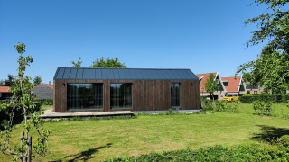 Kleines Holzhaus im Ferienpark Eigen Wijze in den Niederlanden mit grünem Rasen und klarem Himmel.