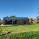 Lille træhus i Holiday park Eigen Wijze i Holland, omgivet af græsplæne og blå himmel.