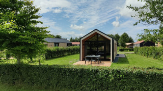 Casa pequeña moderna en Holiday park Eigen Wijze en Países Bajos, rodeada de vegetación y árboles.