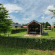 Moderne tiny house på Holiday park Eigen Wijze i Holland, omgivet af grønne buske og træer.