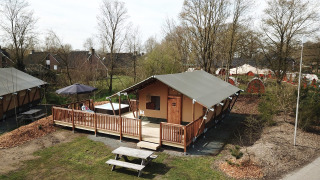 Safari-telt med wellness-område og træterrasse på Holiday Park Sallandshoeve, Nederlandene, omgivet af natur.