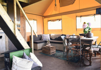Hyggelig indretning af Beach Lodge Big med spisebord, sofa og træelementer i Duynpark Het Zwanenwater.