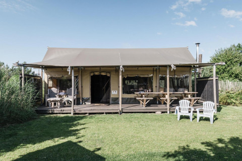 Foto exterior de Wood Lodge en Duynpark Het Zwanenwater, Países Bajos, con porche y césped verde.