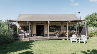 Buitenfoto van de Wood Lodge in Duynpark Het Zwanenwater in Nederland, met terras en gazon.