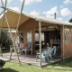 Udendørs lodgetelt på Duynpark Het Zwanenwater i Holland med trædæk, stole og picnicbord på græsplæne.