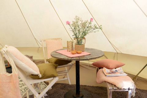 Sfeervol interieur van Tipitent de Jutter bij Duynpark Het Zwanenwater met tafel, stoelen en bloemen.