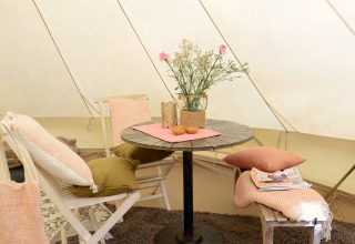Sfeervol interieur van Tipitent de Jutter bij Duynpark Het Zwanenwater met tafel, stoelen en bloemen.
