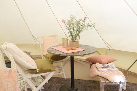 Interior acogedor del Tipitent de Jutter en Duynpark Het Zwanenwater con mesa, sillas, cojines y flores.