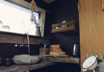 Rincón de cocina rústica en Tipitent de Jutter en Duynpark Het Zwanenwater, Países Bajos, con fregadero de piedra.