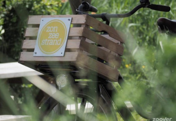 Bicicleta con caja de madera que dice 'zon zee strand' frente al Tipitent de Jutter en Duynpark Het Zwanenwater, Países Bajos.