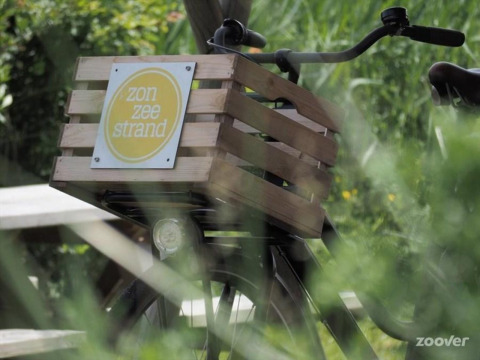 Bicicleta con caja de madera que dice 'zon zee strand' frente al Tipitent de Jutter en Duynpark Het Zwanenwater, Países Bajos.