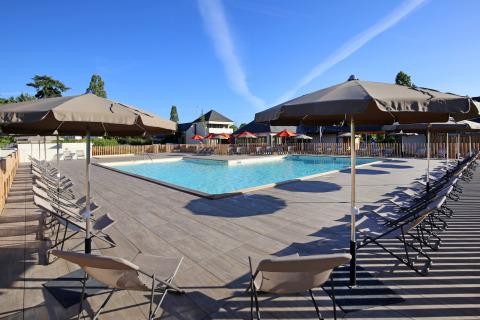 Piscina exterior con tumbonas y sombrillas en Camping d'Angers - Lac de Maine, Francia.