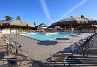 Outdoor swimming pool with deck chairs and umbrellas at Camping d'Angers - Lac de Maine, France.