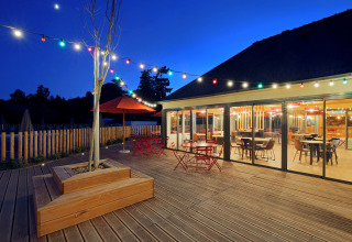 Abendliche Terrasse mit Lichterketten und bunten Tischen im Camping d'Angers - Lac de Maine in Frankreich.