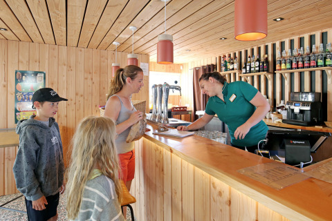 Familia pide en barra de madera en Camping d'Angers - Lac de Maine, parque vacacional en Francia.