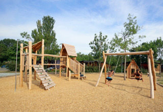 Houten speeltuin met schommels bij Camping d'Angers - Lac de Maine, kinderen spelen in de zon.