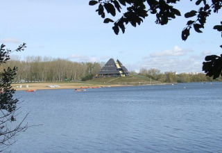 Zicht op het meer aan Camping d'Angers - Lac de Maine met een piramidevormig gebouw op de achtergrond.