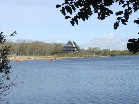 Blick auf den See bei Camping d'Angers - Lac de Maine mit pyramidenförmigem Gebäude im Hintergrund.