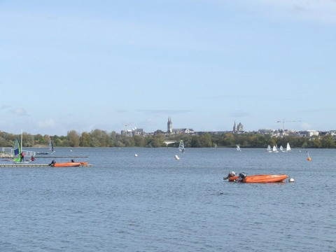 Vista del lago en Camping d'Angers - Lac de Maine con veleros y kayaks en un parque vacacional francés.