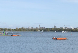 Vista del lago en Camping d'Angers - Lac de Maine con veleros y kayaks en un parque vacacional francés.