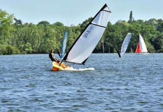 Aficionados disfrutan de la vela y el windsurf en el lago cerca de Camping d'Angers - Lac de Maine, Francia.