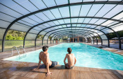 To personer sidder ved en overdækket swimmingpool i Village Huttopia Lac de Rillé, Centre-Val de Loire, Frankrig.