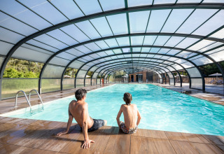 To personer sidder ved en overdækket swimmingpool i Village Huttopia Lac de Rillé, Centre-Val de Loire, Frankrig.
