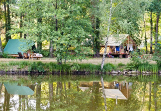 Kampeerplek aan het meer bij Village Huttopia Lac de Rillé, Centre-Val de Loire, met tenten in het groen.