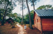 Un niño corre por un sendero entre cabañas de madera en Huttopia Lac de Rillé, Centro-Valle del Loira, Francia.
