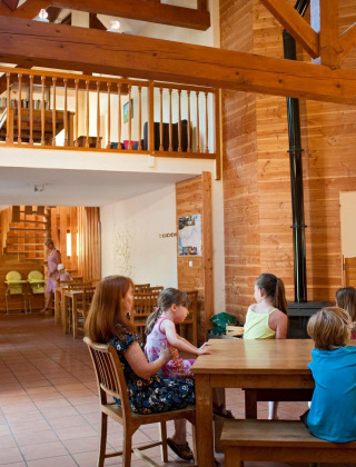 Niños y adultos disfrutan del área común de una acogedora cabaña en Village Huttopia Lac de Rillé, Francia.