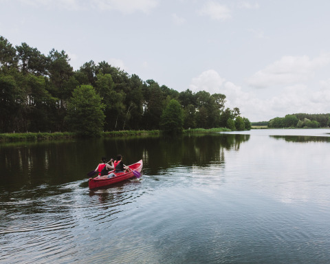 Dos personas remar en una canoa roja sobre un tranquilo lago cerca de Rillé, en Centre-Val de Loire, Francia.