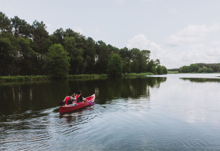Twee mensen peddelen in een rode kano op een rustig meer bij Rillé in Centre-Val de Loire, Frankrijk.