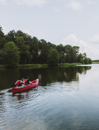 Dos personas remar en una canoa roja sobre un tranquilo lago cerca de Rillé, en Centre-Val de Loire, Francia.