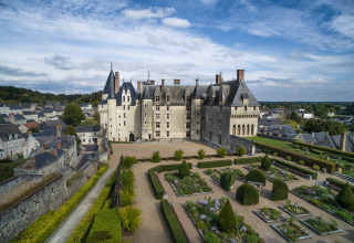 Luchtfoto van een groot kasteel met aangelegde tuinen en omringende woningen in de buurt van Rillé, Frankrijk.