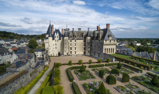 Vista aérea de un majestuoso castillo con jardines formales y edificios alrededor cerca de Rillé, Francia.