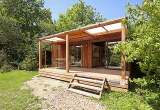 Houten bungalow met terras bij Camping de Lyon in Auvergne-Rhône-Alpes, Frankrijk, omringd door natuur.