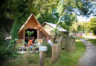 Gezin kampeert bij Camping de Lyon in Auvergne-Rhône-Alpes, Frankrijk, omgeven door groene natuur.