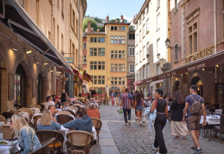 Folk nyder at sidde og gå langs brostensbelagt gade med caféer i Dardilly, Auvergne-Rhône-Alpes, Frankrig.