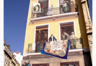 Un mural colorido en un edificio de Lyon, Francia, muestra personas en balcones y ventanas.