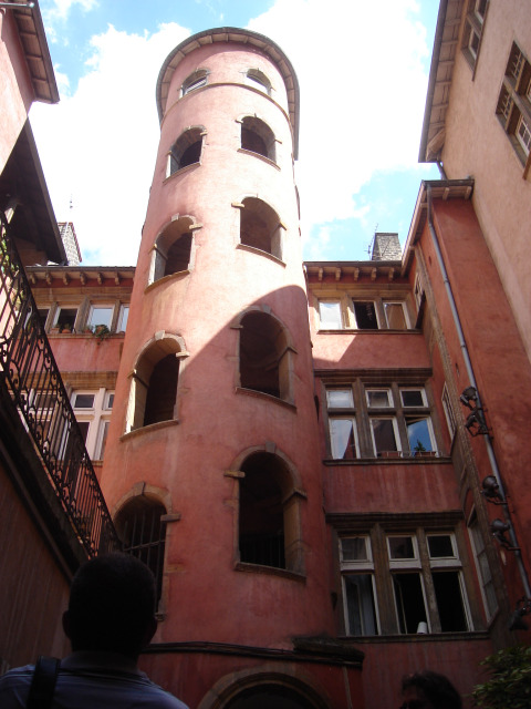 Torre redonda con arcos abiertos en edificio rojo en Camping de Lyon, Auvergne-Rhône-Alpes, Francia.