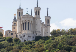 The Basilica of Notre-Dame de Fourvière rises majestically above green hills in Lyon, France.
