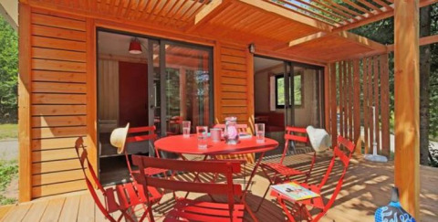 Chalet Ottawa en Camping d'Angers - Lac de Maine, Francia, terraza de madera y muebles rojos en el exterior.