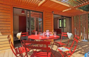 Chalet Ottawa en Camping d'Angers - Lac de Maine, Francia, terraza de madera y muebles rojos en el exterior.