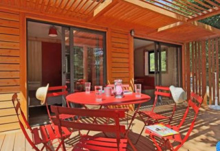 Chalet Ottawa en Camping d'Angers - Lac de Maine, Francia, terraza de madera y muebles rojos en el exterior.