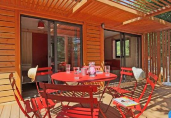 Chalet Ottawa en Camping d'Angers - Lac de Maine, Francia, terraza de madera y muebles rojos en el exterior.
