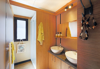 Baño moderno en el Chalet Ottawa de Camping d'Angers - Lac de Maine, Francia, con dos lavabos y detalles de madera.