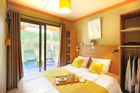 Dormitorio luminoso y moderno en Chalet Ottawa de Camping d'Angers - Lac de Maine, Francia, con vista a la terraza.