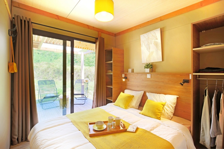 Dormitorio luminoso y moderno en Chalet Ottawa de Camping d'Angers - Lac de Maine, Francia, con vista a la terraza.