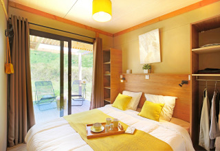 Dormitorio luminoso y moderno en Chalet Ottawa de Camping d'Angers - Lac de Maine, Francia, con vista a la terraza.