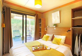 Dormitorio luminoso y moderno en Chalet Ottawa de Camping d'Angers - Lac de Maine, Francia, con vista a la terraza.